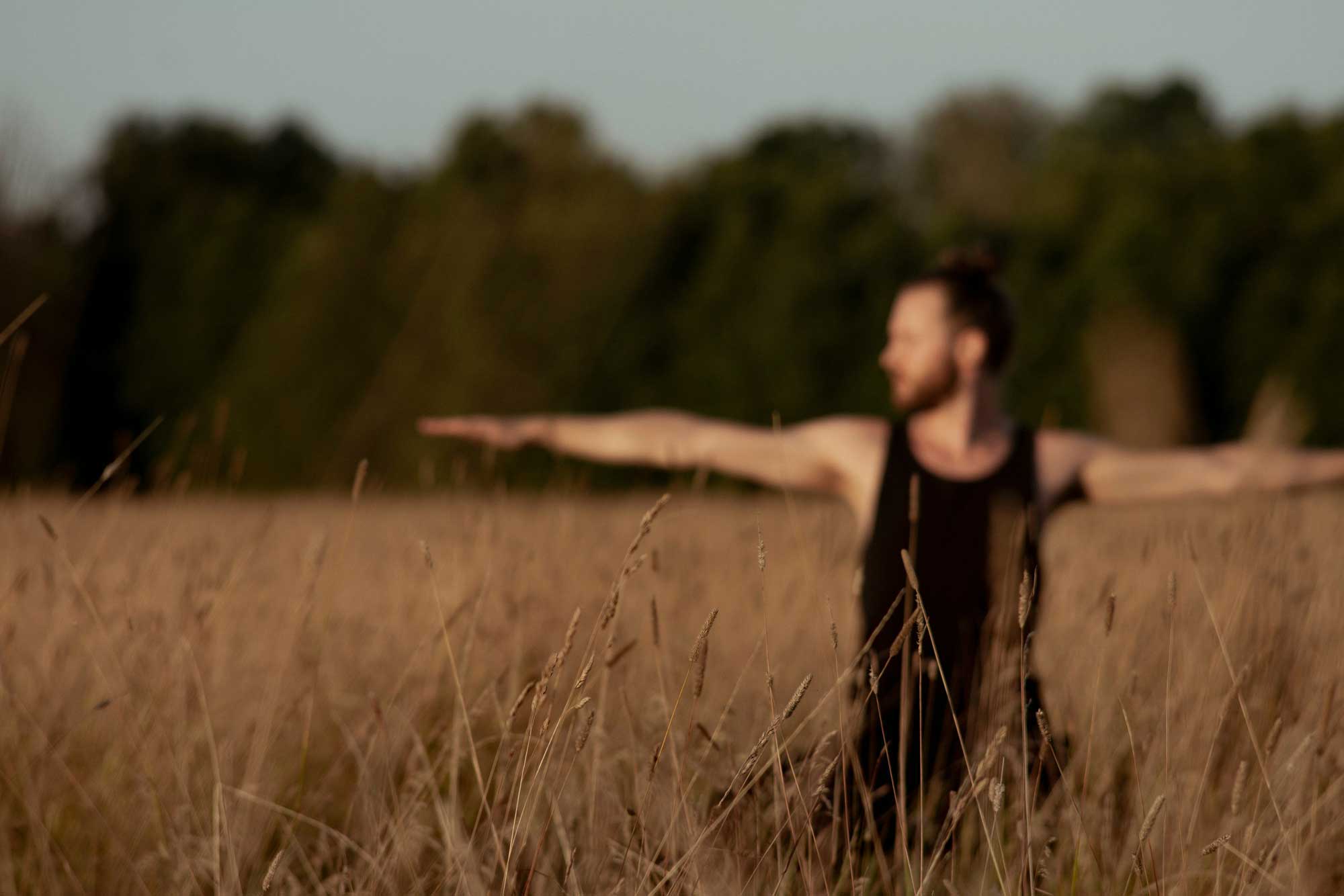Man doing a yoga pose in a field in summer